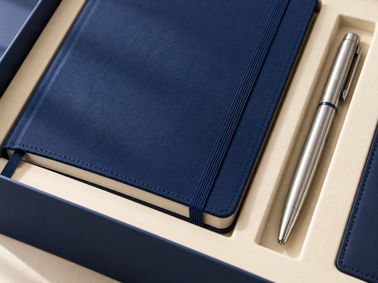 Product design concept close-up of the navy notebook cover, paper block and silver pen