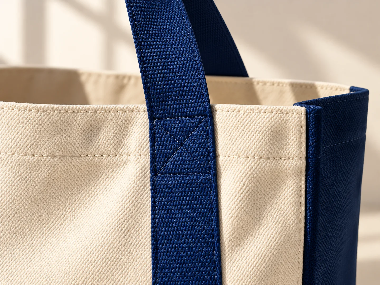 Product design concept close-up of the navy tote handle attachment and ivory canvas texture