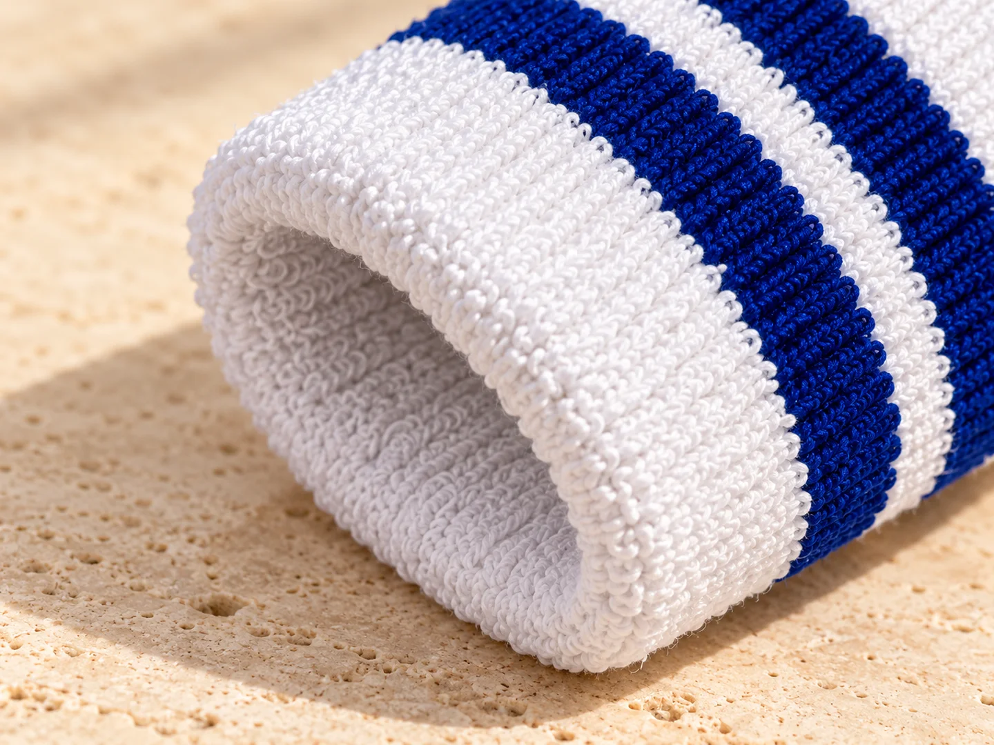 Product design concept close-up of an ivory terry cuff with two navy knitted stripes