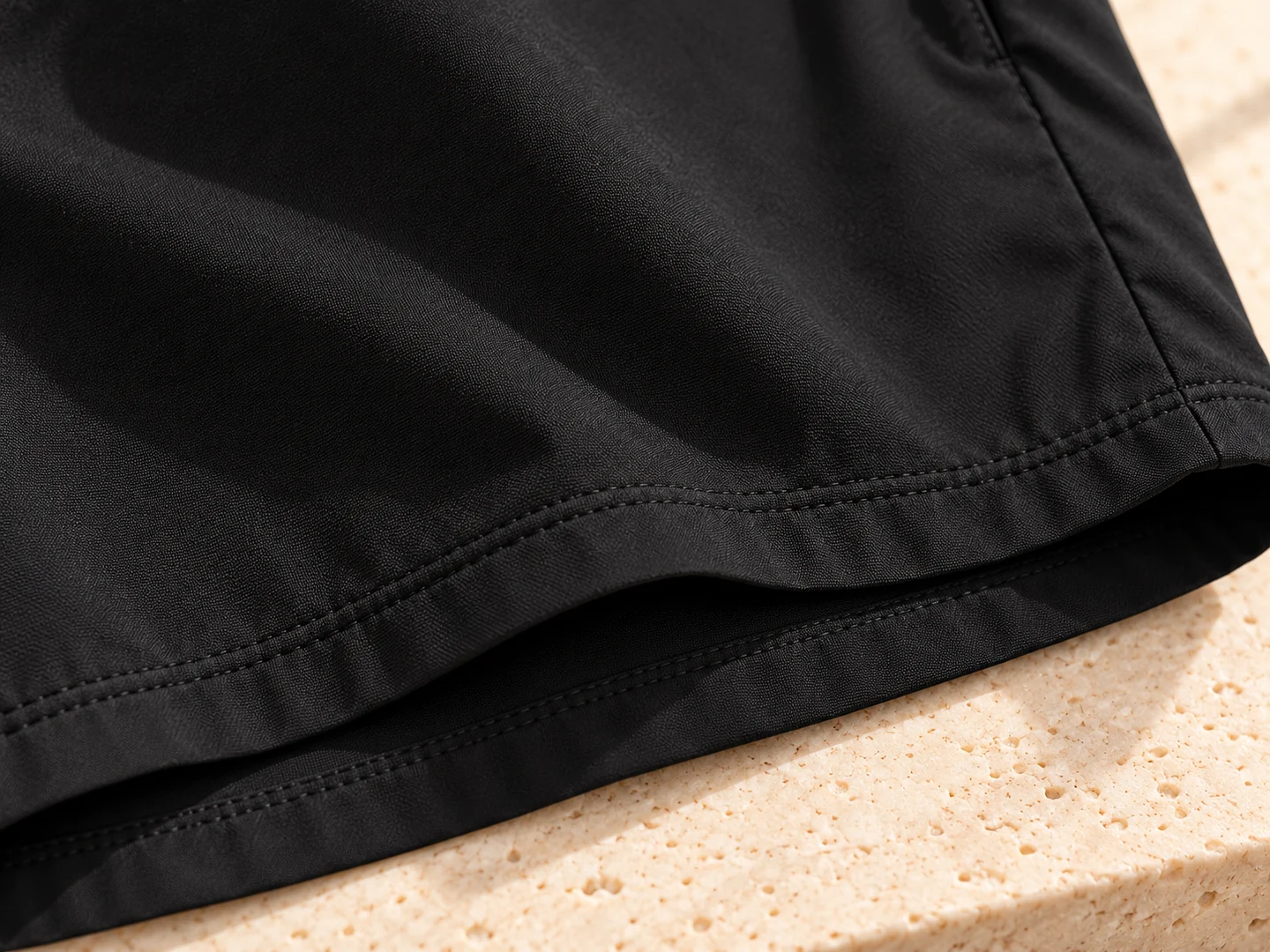 Macro view of black cloth texture and double-stitched leg hem; product design concept