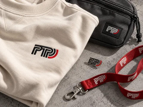 AI-generated PTP custom-branding concept showing embroidered apparel, a woven label, printed lanyard and enamel pin